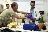 U.S. Air Force Maj. Norman Zellers assists a general medicine doctor with the setting of a broken arm.