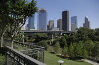 A railing from an apartment complex and the Houston skyline overlook the Buffalo Bayou as it snakes its way into downtown.