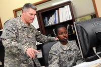 U.S. Army Maj. Theodore P. Byrne helps Staff Sgt. Evelyn Hurry finalize tax documents at the Camp As Sayliyah legal office in Qatar.