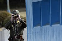 North Korean soldier looks through a pair of binoculars at Panmunjom