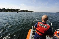 A boat crew member from Coast Guard Station Gloucester, Mass., monitors swimmers off Niles Beach.