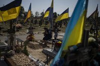 A woman cries at her son's grave who died fighting in the war, as Ukrainians mark Independence Day