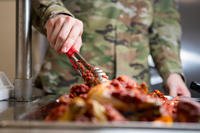 An airman food-service apprentice serves chicken at the Marshall Dining Facility at Kadena Air Base, Japan, Oct. 28, 2021. 