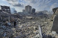 Palestinians walk through buildings destroyed by Israeli airstrikes