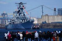 People gather in Gloucester City, N.J., to view the USS New Jersey as it moves down the Delaware River.