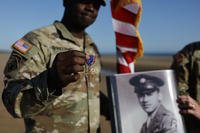 A soldier shows a Distinguished Service Cross while another holds a portrait of Waverly Woodson.