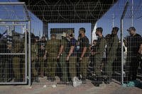 Israeli soldiers gather at the gate to the Sde Teiman military base, as people protest in support of soldiers being questioned for detainee abuse