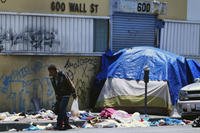 Homeless man walks along a street lined with trash in downtown Los Angeles