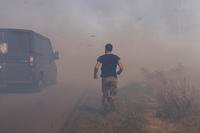 A Ukrainian serviceman runs to help farmers extinguish a burning field