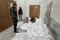 Palestinians gather in a morgue with the bodies of their relatives killed in Israeli airstrikes in the city of Khan Younis