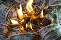 Flames appear to burn a pile of $50 bills, which take up the whole frame.