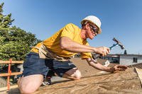 Boatswain’s mate Zach Lee, USS Anchorage (LPD 23), hammers nails into the roof of a house during a Habitat for Humanity neighborhood rebuild project in Long Beach, California, during Los Angeles Fleet Week.