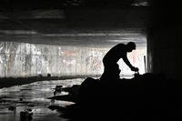 In this Dec. 5, 2020, file photo, Dave Marlon of CrossRoads of Southern Nevada offers some items to an individual during an outreach in the underground tunnels to provide counseling, food and water to the homeless living beneath the city in Las Vegas.