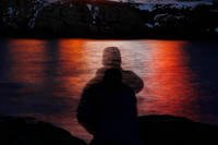 A man is silhouetted against lights reflected in the waters off Cape Neddick in Maine.