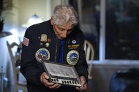 Navy veteran Bob Fernandez holds a photograph of the USS Curtiss.