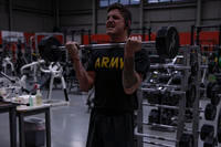 A soldier assigned to the 1st Infantry Division performs barbell biceps curls during their morning physical training session at Leonard Fitness Center on Fort Riley, Kansas.