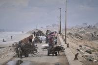 Displaced Palestinians carrying their belongings as they move between southern and northern Gaza.