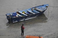 Del Mar lifeguards look over a capsized boat on the beach Monday, May 5, 2025, at Torrey Pines State beach in San Diego