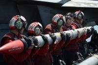 sailors load an AIM-120C missile into an F/A-18E Super Hornet
