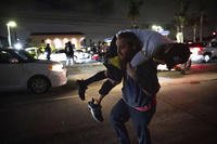 A person carries an injured protester to cover during a protest in Compton, California.