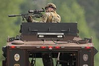 A law enforcement officer trains his rifle towards a house as the officers search for shooting suspect Vance Boelter