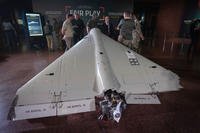 Visitors look at a damaged Iranian-made drone, Shahed