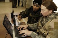 U.S. Army Sgt. Sarah L. Blair enters vital information for Iraqi policemen into a laptop computer as Iraqi aide Antonio translates at an Iraqi police station in Samarra, Iraq.