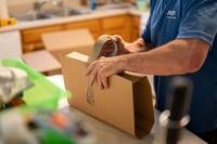 A mover tapes a small item in cardboard.
