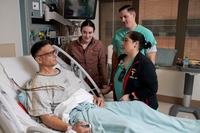 A man in a hospital bed surrounded by health care providers.