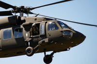 U.S. Army National Guard Staff Sgt. Gabe Cherian, a crew chief, looks out the door of a UH-60 Black Hawk helicopter to ensure clearance to land at the Ike Skelton Training Site in Jefferson City, Missouri.