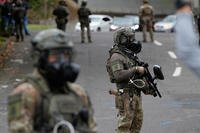 Immigration and Customs Enforcement agents stand outside an ICE facility during a protest in Portland, Ore.