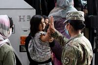 Army soldier gives a high five to a small child from Afghanistan.