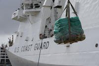 A palette loaded with bundles of seized cocaine and marijuana is lowered down by a crane, as the U.S. Coast Guard unloads more than one billion dollars worth of seized drugs from the Coast Guard Cutter James at Port Everglades, Thursday, Feb. 17, 2022, in Fort Lauderdale, Fla. (AP Photo/Rebecca Blackwell)