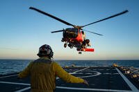 U.S. Coast Guard Ensign Dennis O’Shea directs an MH-60 Jayhawk helicopter from Coast Guard Air Station Ventura to land on the flight deck of Coast Guard Cutter Bertholf (WMSL 750), July 8, 2025. Training consistency across the Coast Guard allows for seamless operations between units. (U.S. Coast Guard photo by Petty Officer 3rd Class Avery Tibbets)