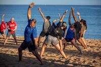 Soldiers in civilian workout clothes stretch on a beach.