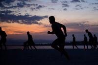 A silhouette of an airman running on the beach at sunrise.