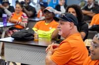 Veterans in matching orange shirts attend a meeting.