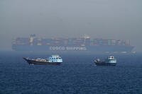 Two traditional dhows sail by a large container ship in the Strait of Hormuz.