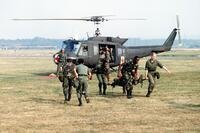 Military medics runs from a helicopter with a patient on a stretcher.