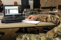 A uniformed soldier's arm rests on a notepad.