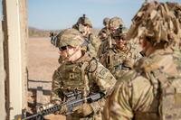 Soldiers in battle uniforms encounter a wall.