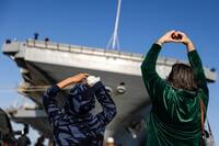 Loved ones make hearts with their hands for their sailor on board while the USS George H.W. Bush (CVN 77) prepares to pull away from Naval Station Norfolk for deployment.