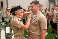 Diana Flowers pins new collar devices on her husband, Michael Flowers, during a frocking ceremony June 30, 2014, at Naval Base Coronado. Both were frocked to senior chief. (US Navy photo by Paul Coover)