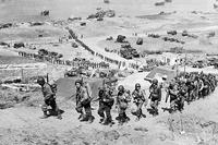 This picture of Omaha Beach at the end of the invasion's first day shows the bluff Gen. Cota's men had to climb under fire. Note the bunker the men are walking past. (National Archives)