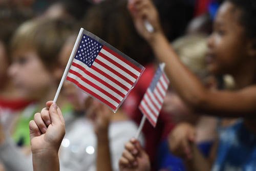 Students at Jeff Davis Elementary School wave U.S. flags during a Veterans Day celebration in Biloxi, Mississippi, Nov. 8, 2018. (U.S. Air Force photo/Kemberly Groue)