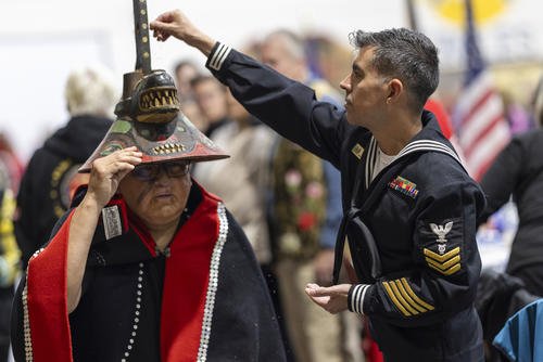 A member of the U.S. Navy sprinkles tobacco on top of a killer whale clan hat