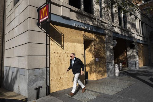 Pedestrian walks past boarded up stores near the White House in Washington