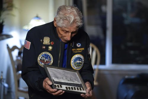 Navy veteran Bob Fernandez holds a photograph of the USS Curtiss.