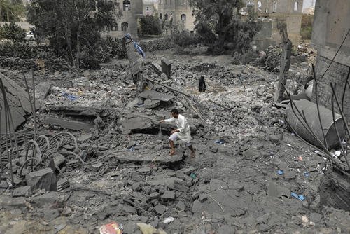 A Yemeni walks over the debris of a destroyed building following U.S. airstrikes