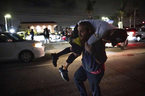A person carries an injured protester to cover during a protest in Compton, California.